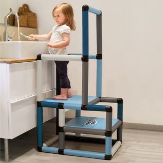 Girl on learning tower brushing her teeth
